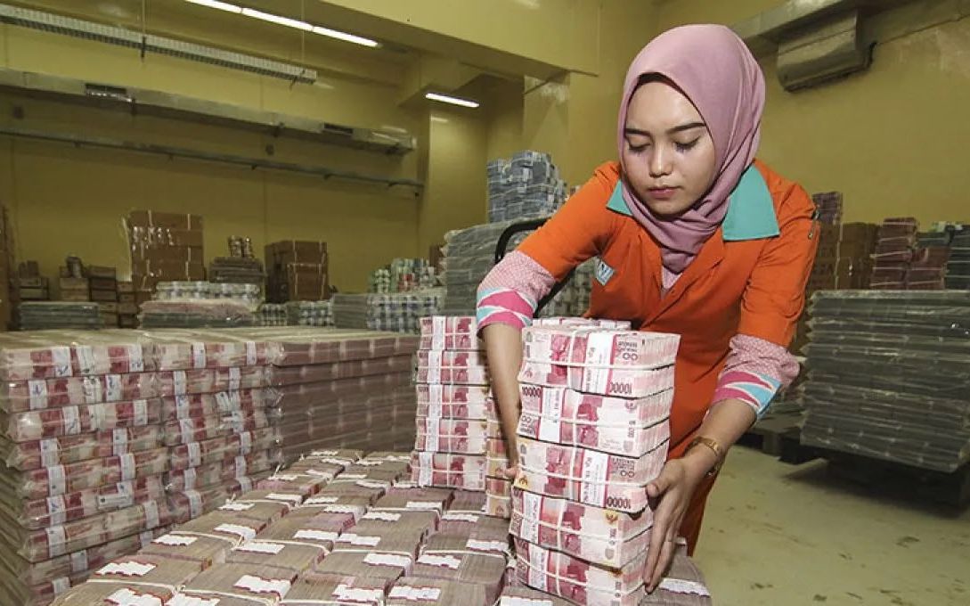 Ilustrasi - Petugas menata tumpukan uang kertas rupiah saat melakukan persiapan pengisian ATM.