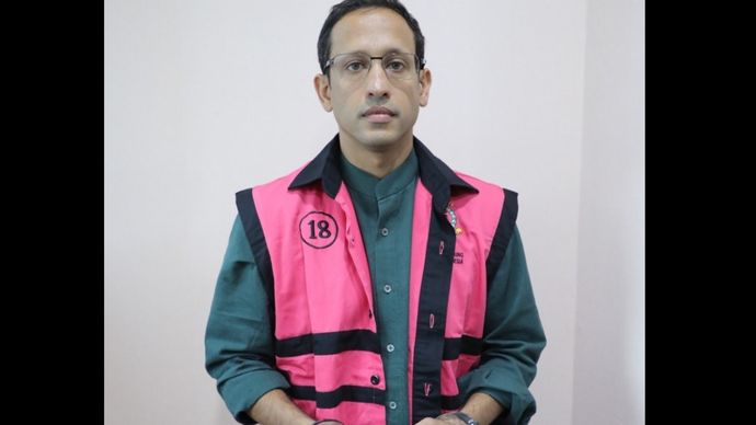 Nadiem Makarim saat mengenakan rompi pink dan kedua tangannya diborgol. 